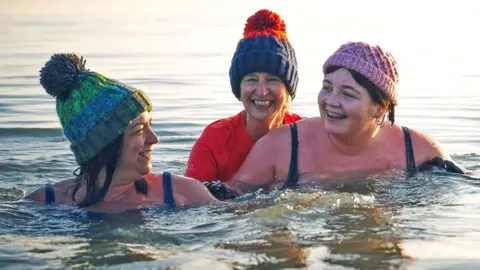 Getty Images Family having a moment together messing about while winter sea swimming 
