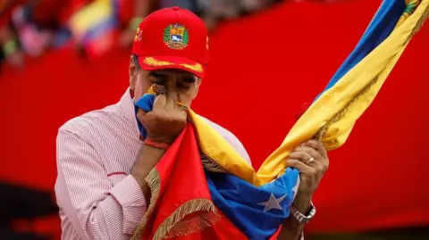 Reuters Venezuela's President Nicolas Maduro kisses a Venezuelan flag during a ceremony to swear in new community-based organisations