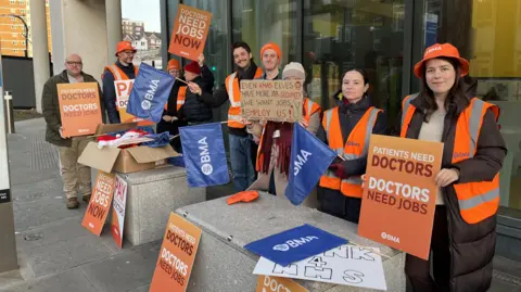 George Carden/BBC People wearing hi vis jackets and holding b anners on a picket line in Brighton