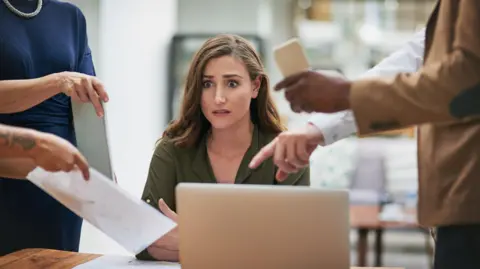 Getty Images Shot of a young businesswoman looking anxious in a demanding office environment